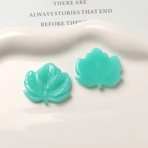 Detail of mint green resin leaf charms with realistic vein texture on a decorative plate