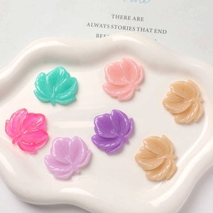 Macro detail of colorful resin leaf charms with realistic vein textures in a white dish