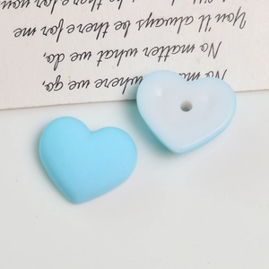 Macro detail of sky blue matte heart acrylic beads with central hole for DIY jewelry