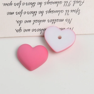 Close-up of matte heart-shaped acrylic beads for DIY earring crafts in pink and white