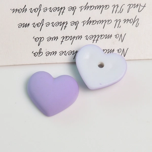 Macro detail of heart-shaped acrylic beads with a matte macaron finish for DIY jewelry