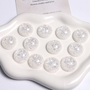 Détail macro de cabochons en résine nacrée de 25mm pour loisirs créatifs sur plateau blanc