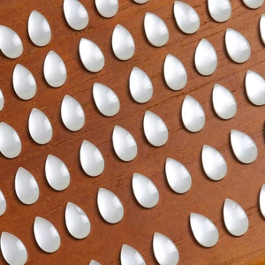 Flat lay of teardrop-shaped white mother of pearl resin cabochons on wood surface