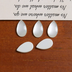 Macro shot of five teardrop-shaped white opal resin cabochons for DIY earring jewelry making