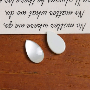 Close-up of white teardrop resin charms with pearlescent finish for DIY jewelry