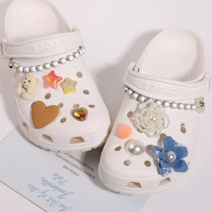 Beige Clogs dekoriert mit Perlenketten, Teddybären und floralen Anhängern