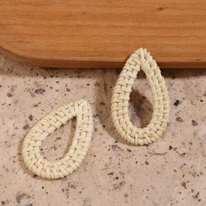 Detalle de dijes de ratán trenzado crema para creación de joyería artesanal DIY