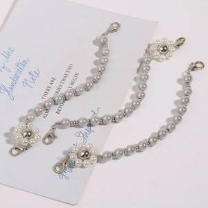 Details von grauen Perlen-Schuhketten mit weißen Blumen und silbernen Karabinerhaken