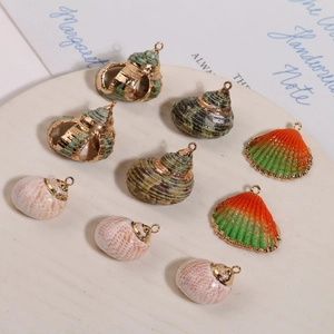 Détail de pendentifs en coquillage naturel avec bordure dorée sur plateau blanc