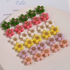 Close-up of assorted colorful resin flower beads with golden stamens for DIY jewelry