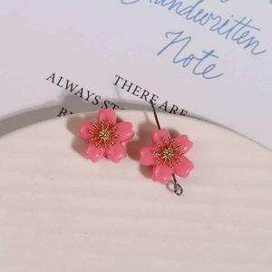 Detailed macro view of pink resin cherry blossom pendant with golden flower stamens