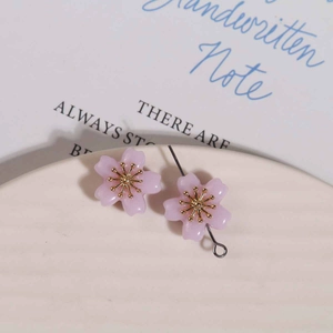 Detail of pink resin flower pendants with golden stamens in a white ceramic dish