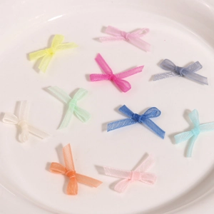 Vue macro de nœuds décoratifs en organza coloré pour ongles sur assiette blanche