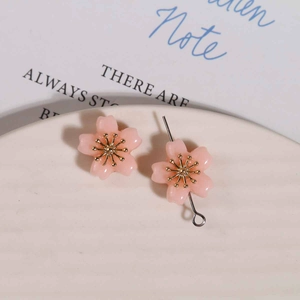 Detailed view of pink resin cherry blossom flower charms with golden center on ceramic tray