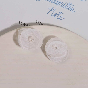 Makroaufnahme von handgefertigten weißen Mesh-Stoffblumenohrringen mit Perle auf Keramiktablett