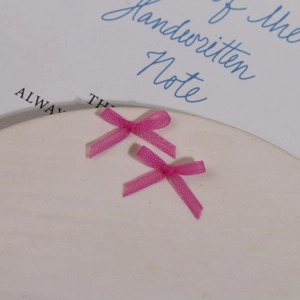 Gros plan de deux nœuds délicats en organza rose pour l'art des ongles sur une assiette blanche