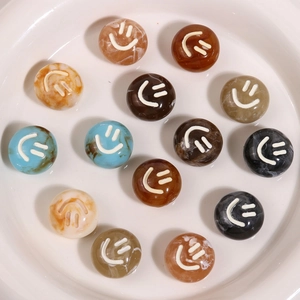 Colorful resin marble round beads with white smile faces in a white ceramic dish