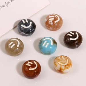 Detailed view of DIY resin charms with marble texture and white smiley faces
