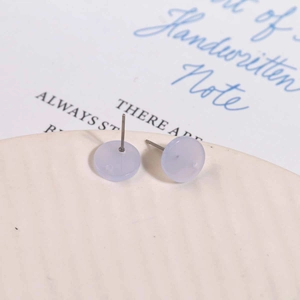 Macro detail of lavender jelly acrylic stud earrings with silver pins on a ceramic dish