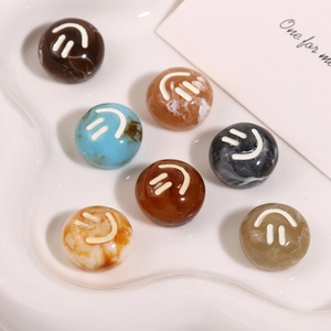 Flat lay of colorful marble resin beads with smiley face motifs on a ceramic tray