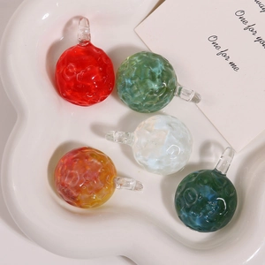 Detailed macro view of textured glass bead charms in five colors on a ceramic tray