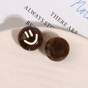 Macro shot of brown marble-textured resin round bead with a white smiley face print