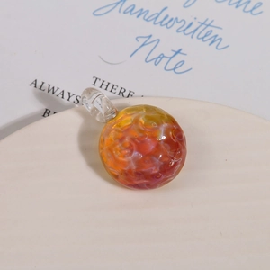 Macro view of a spherical gradient glass bead with wavy texture and clear hanging loop