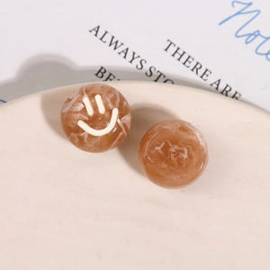 Detail of amber resin flatback bead with marble texture and white smiley face design