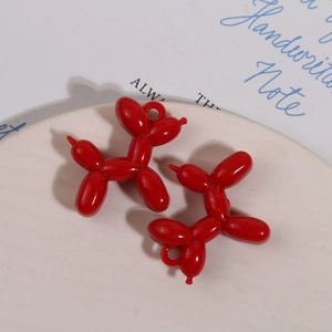 Detail van glanzende rode ballonhond hangers voor DIY sieraden op een wit bord