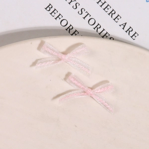 Macro shot of two light pink organza 3D butterfly bows on a white ceramic plate