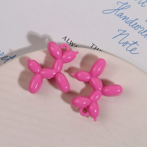 Detail van roze acryl ballonhond bedeltjes op keramische schaal voor sieraden