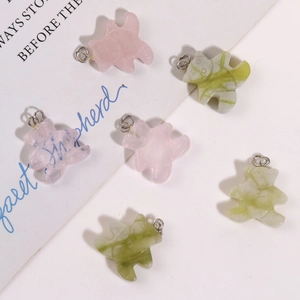 Détail de pendentifs ours en quartz rose et vert avec boucles en métal sur papier
