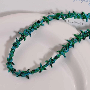 Primer plano de cuentas de estrella de mar azul y verde con salpicaduras sobre bandeja blanca
