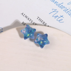 Macro de boucles d'oreilles étoiles en résine aurore avec paillettes irisées sur plateau