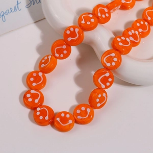 Macro detail of 14mm bright orange smile face glass beads for DIY jewelry making