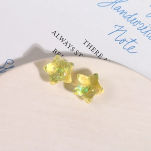 Vue macro de breloques étoiles en résine Aurora avec paillettes irisées dans un plat