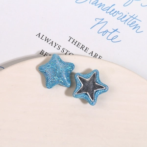 Gros plan sur les patchs étoiles en paillettes bleues et tissu miroir argenté sur plateau