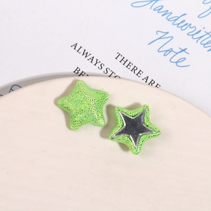 Détail de boutons étoiles en tissu pailleté vert néon avec base en métal brillant