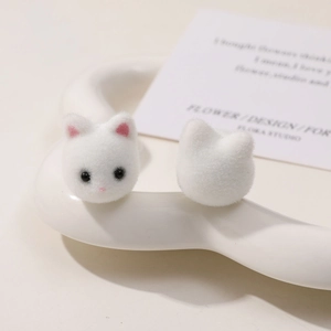 Nahaufnahme süßer weißer beflockter 3D-Katzenanhänger auf Keramikschale für DIY-Schmuck