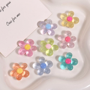 Macro shot of colorful glitter resin flower charms for DIY accessories on a white plate