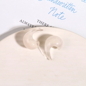 Dettaglio degli orecchini vintage in resina a forma di C con finitura bianco crema