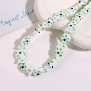 Detail of fish-shaped ceramic beads with green dots and blue evil eye patterns
