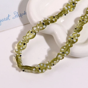 Macro shot of green fish-shaped ceramic beads with hand-painted polka dots for DIY jewelry