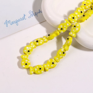Macro view of handmade yellow ceramic fish bead with white polka dots for jewelry DIY