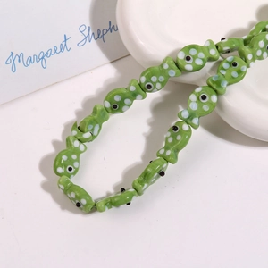 Close-up of green ceramic fish beads with white polka dots for handmade jewelry crafts