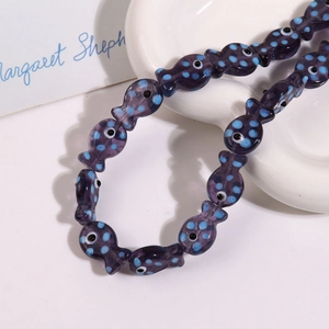 Macro view of purple fish-shaped ceramic beads with blue dots for DIY jewelry making