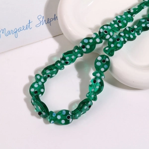 Detailed view of green ceramic fish beads with white polka dots for DIY jewelry making