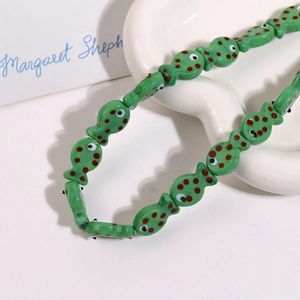Macro view of handmade green ceramic fish beads with red polka dots for DIY jewelry