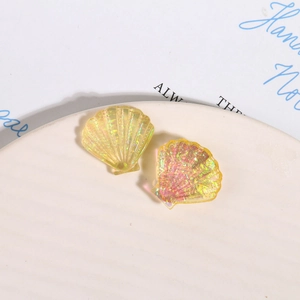 Dettaglio macro di ciondoli a conchiglia in resina gialla con glitter dorati scintillanti
