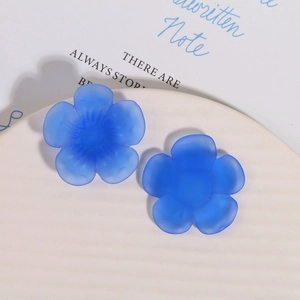 Macro shot of matte dark blue resin flower charms with textured centers on white plate